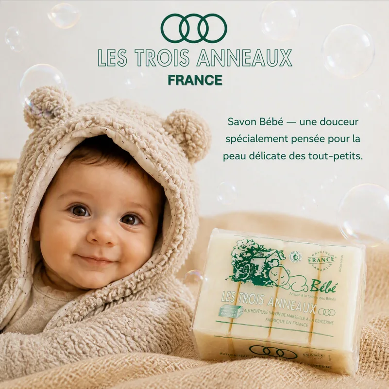 Bébé souriant dans un peignoir à oreilles d'ourson, à côté du pack Savon Bébé