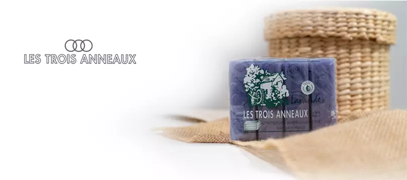 Pack de savon de Marseille à la lavande posé sur de la toile de jute, devant un panier en osier